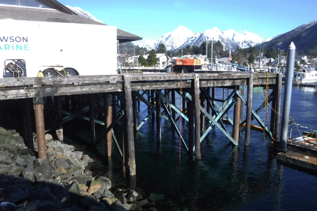 Sitka, Alaska's Crescent Harbor High Load Dock on a sunny day with mountains in the background.