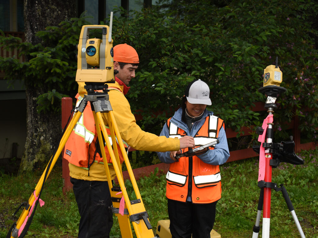 Two people working together on a land surveying project in a residential neighborhood.